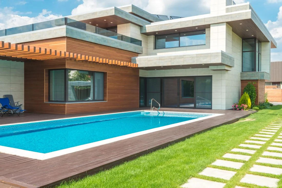 Glass-fronted house with pool and garden Modern glass-fronted house with a swimming pool and green garden.