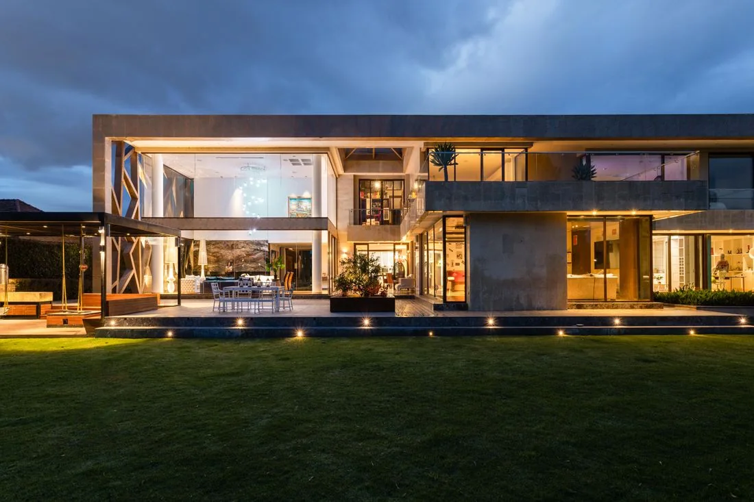 Contemporary villa illuminated at dusk with broad glass windows.
