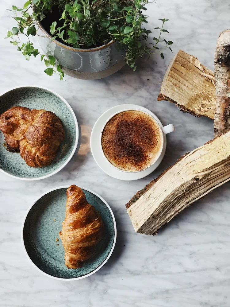 Fresh croissants and cappuccino on a marble café table.
