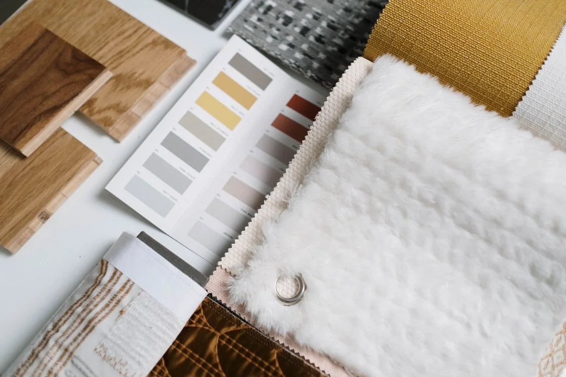 Wood samples, neutral color swatches and textured fabrics arranged on a table.